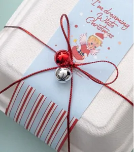 Détail en gros plan des cloches en métal de Noël accessoire d'emballage cadeau avec carte et ruban.