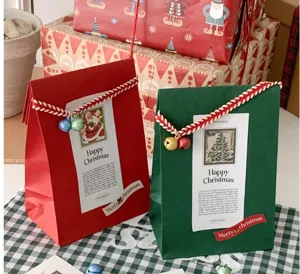 Bolsa de regalo de papel plano rojo y verde de Navidad vista de detalle con campana y etiquetas.