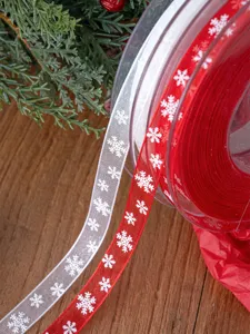 Vista dettagliata dei rotoli di nastro in chiffon con fiocchi di neve natalizi per pacchi regalo.