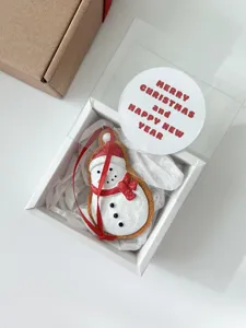Details of Christmas snowman gift box ornament with festive sticker and red ribbon design.