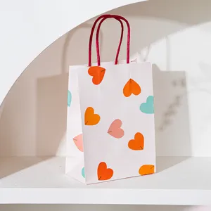 Gros plan détail du sac cadeau blanc avec imprimé cœur coloré et poignées rouges sur étagère.