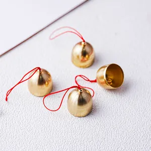 Kleine gouden metalen bellen met rode touwtjes voor kerst DIY windgongen decoraties.