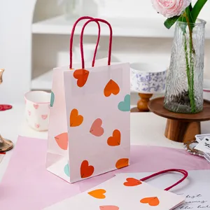 Sac cadeau en papier rose cœur vue détaillée, sachet d'emballage pâtisserie avec poignées rouges.