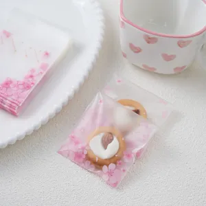 Frosted plastic cookie packaging bags with cute pink cherry blossom designs for gifts.