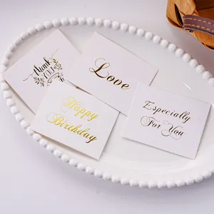 Detail close-up of minimalist white greeting cards featuring elegant gold foil text design.