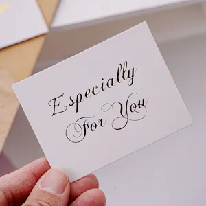 Close-up detail shot of a minimalist white greeting card with elegant gold foil script text.
