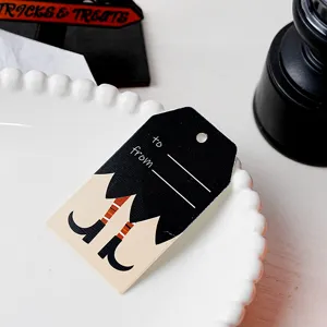 Halloween paper gift tag close-up, witch feet design with to and from lines on white plate.