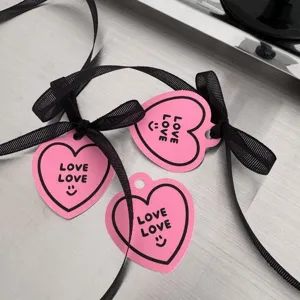 Roze hartvormige cadeaulabels met zwarte linten voor Valentijnsdag en verjaardagsfeestjes.