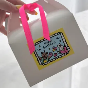 White gift box with pink ribbon and cute birthday sticker featuring bear and rabbit.