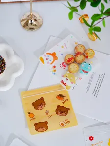 Sachets zippés en plastique transparent et jaune avec motifs d'ours et de fruits en détail.