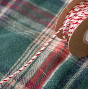 Nahaufnahme von rot-weißer Kordel auf Spule, ideal für DIY-Geschenkverpackungen und Basteln.