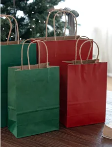 Sacchetti regalo di Natale in carta kraft rossa e verde con manici per feste e doni.