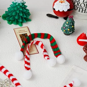 Vista detallada de mini bufandas navideñas de punto con rayas rojas y verdes y pompones.