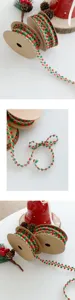 Detailed view of Christmas decorative ribbon with red and green pom-poms and gold trim for DIY.