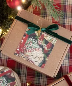 Christmas gift wrapping box with green velvet ribbon bow and holiday greeting card detail.