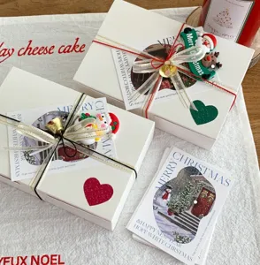 Joli coffret cadeau de Noël avec rubans décoratifs, cloches et cartes de vœux pour les fêtes.