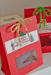 Set de bolsas de papel de regalo de Navidad con lazo de espumillón y etiqueta festiva.