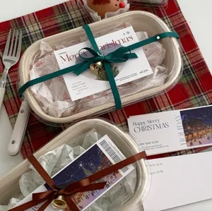Détail de boîte bento de Noël avec beau papier d'emballage, ruban vert et cloches dorées.