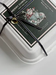 Dettaglio scatola di imballaggio natalizia, confezione regalo quadrata con nastro e adesivo.