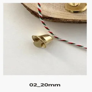 Gros plan d'une petite cloche dorée avec ficelle rouge verte blanche pour déco de Noël DIY.