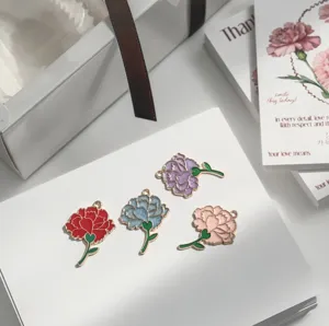 Close-up of colorful carnation enamel charms on white card, ideal for DIY jewelry crafting.
