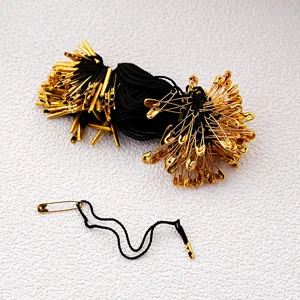 Detail shot of black hang tag strings with gold safety pins and metal tips for clothing tags.