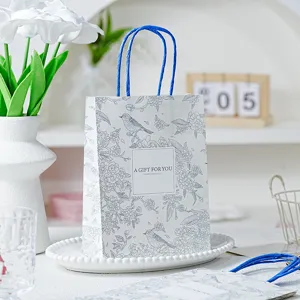 Lente vogel geschenk papieren zak met blauw handvat, elegant bloemdessin verpakking tas.