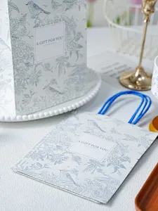Lente vogeltje cadeautas van papier met blauwe handvatten, perfect voor Moederdag.