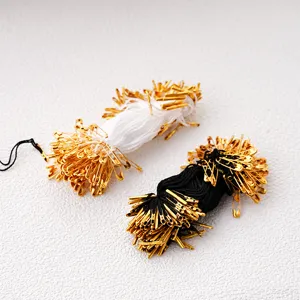 Black and white tag strings with gold safety pins, clothing label fasteners, DIY accessories detail.