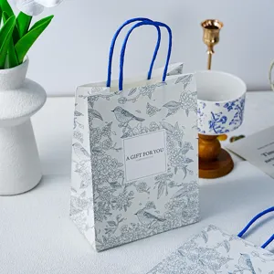 Detail van mooie cadeau papieren zak met blauwe vogel bloemen print en elegante handgrepen.