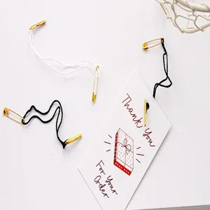 Hang tag strings with safety pins and thank you tags for clothing and gift packaging.