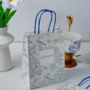 Papieren cadeauzak met bloemenprint en blauwe handvatten, ideaal voor Moederdag en feesten.