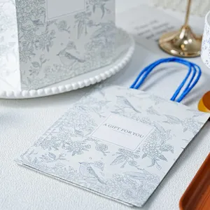 Lente bloem vogel papier geschenkzak met blauw handvat voor verpakking en feest.