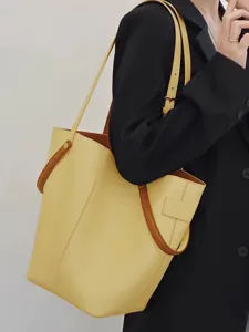 Close-up view of a stylish yellow leather bucket bag with adjustable strap and chic details.