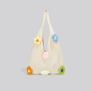 Detailansicht der beigen Strick-Tasche mit bunten handgefertigten Häkelblumen-Verzierungen.