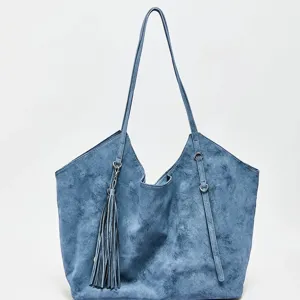 Détail de cabas en suédine bleue avec texture douce, longue bandoulière et charmant pompon.