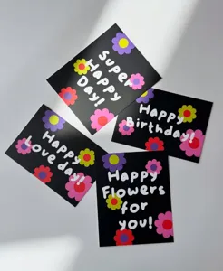 Primer plano de tarjetas de felicitación negras con patrones florales coloridos y texto alegre.