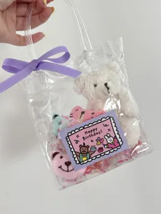 Birthday greeting card packaging set with cute plush bear and transparent handle bag for gifts.