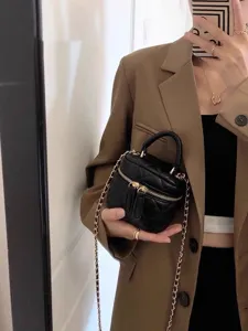 Primer plano detallado del mini bolso acolchado negro sostenido con elegancia.