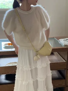 Detailansicht einer eleganten kleinen Umhaengetasche kombiniert mit weissem Oberteil.