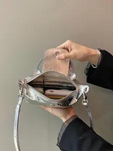 Silver metallic folding dumpling handbag, versatile crossbody shoulder bag with flap design.