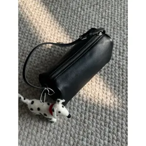 Borsa a mano cilindrica in pelle PU nera con ciondolo a cane, stile minimalista chic.