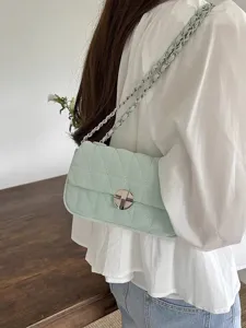 Detailed view of the mint green quilted shoulder bag with chain strap and metal lock.