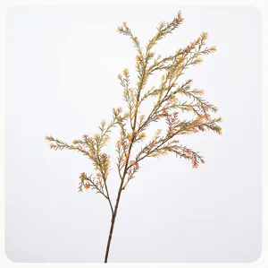 Detail shot of artificial golden pine greenery branch for home decor and floral arrangement.