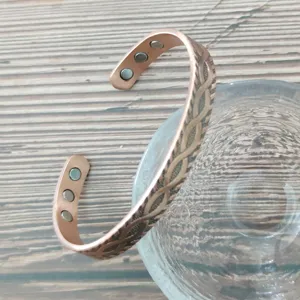 Dettaglio ravvicinato del bracciale in rame regolabile con magneti interni e motivo a otto.