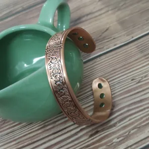 Detailed shot of wide copper magnetic bracelet with vintage pattern and open adjustable design.