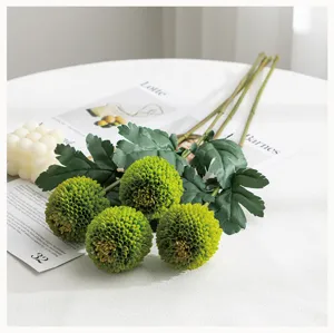 Close-up detail of artificial green pompon chrysanthemum flowers bouquet on white table.