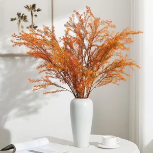 Artificial golden eucalyptus plant branches in white ceramic vase for modern home room decor.
