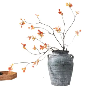 Artificial maple leaf branches with grey vintage vase for autumn home decoration.