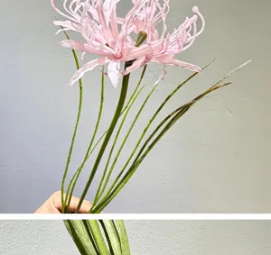 Close-up detail of artificial pink spider lily flower with green stem and leaves for decor.